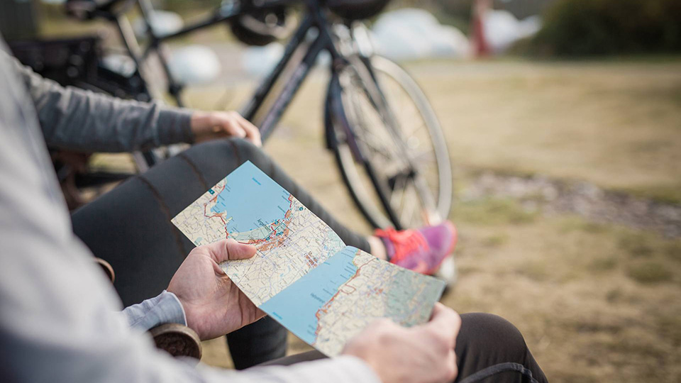 Cyklar i bakgrunden och två personer tittar på en karta.