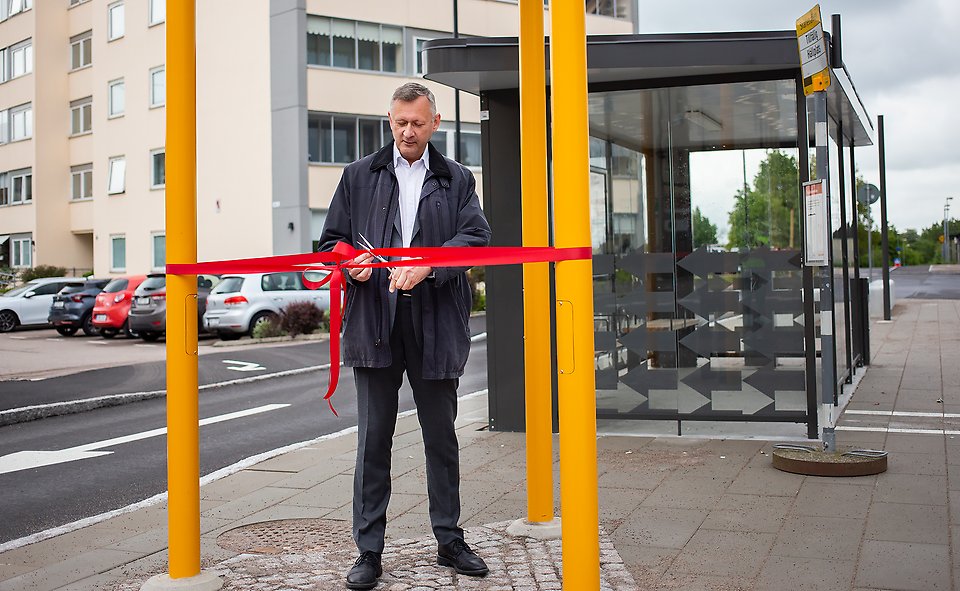 Kommunstyrelsens ordförande Ronny Sandberg klipper ett rött invigningsband vid Åstorps stationsområde.