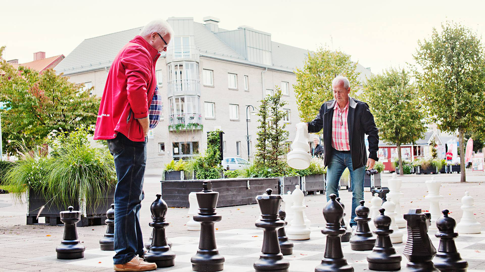Tvä äldre herrar spelar schack utomhus.